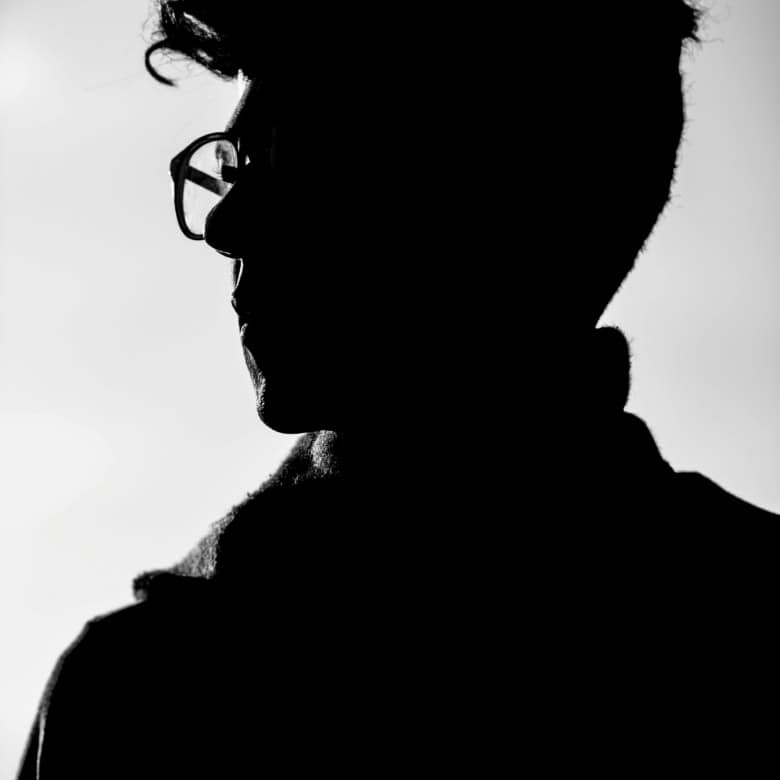 Silhouette of a person with glasses, facing left, in black and white.