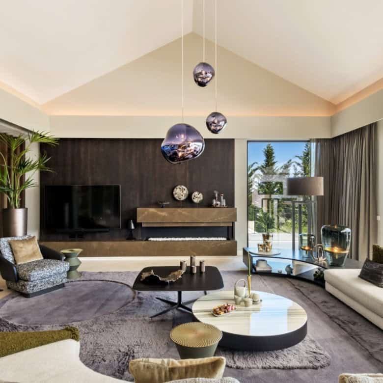 Modern villa living room with stylish furniture and large windows overlooking lush greenery.