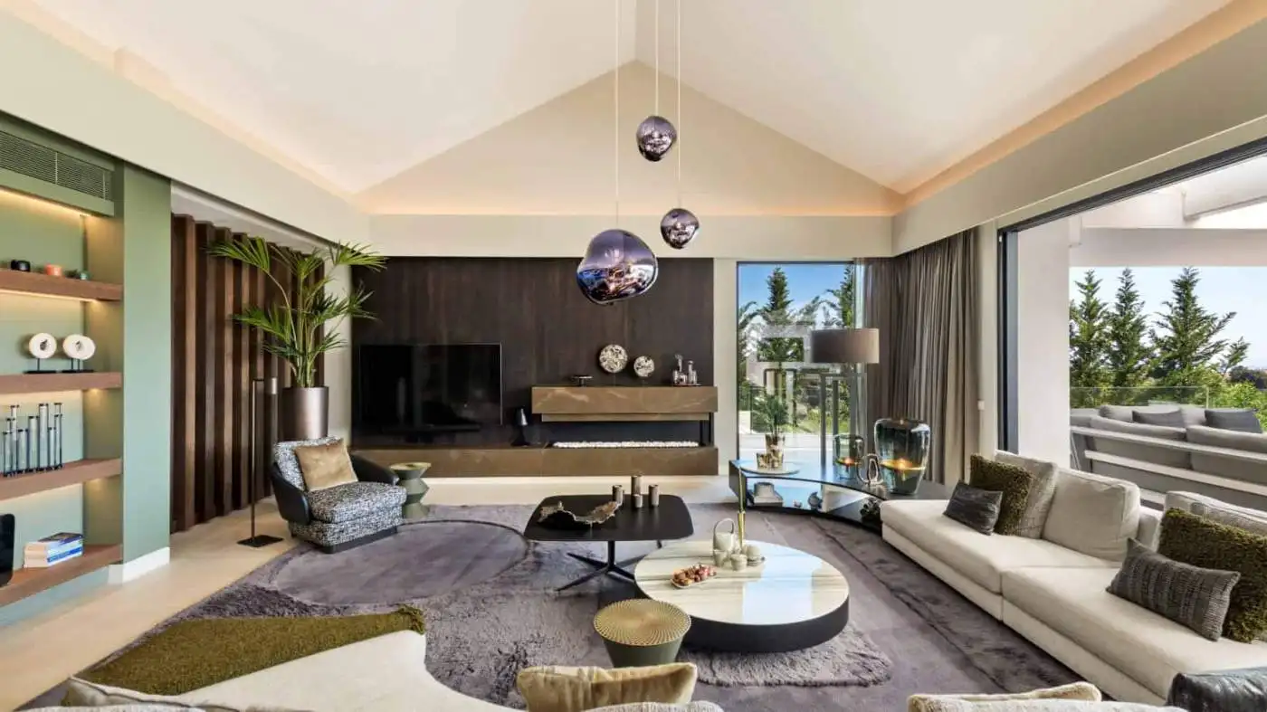Modern villa living room with stylish furniture and large windows overlooking lush greenery.
