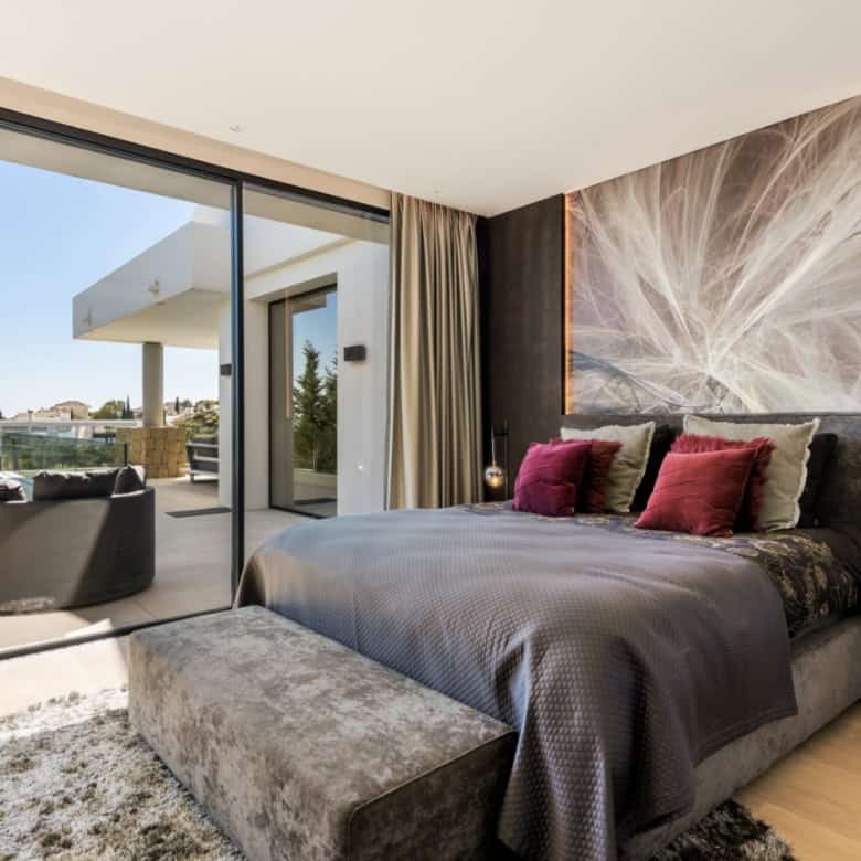 Elegant bedroom with large glass doors opening to a balcony in Los Flamingos Resort. Modern decor wi.