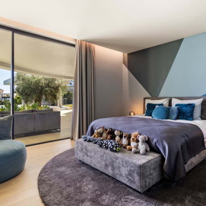 Elegant modern villa bedroom with stylish decor and large glass doors opening to a balcony.