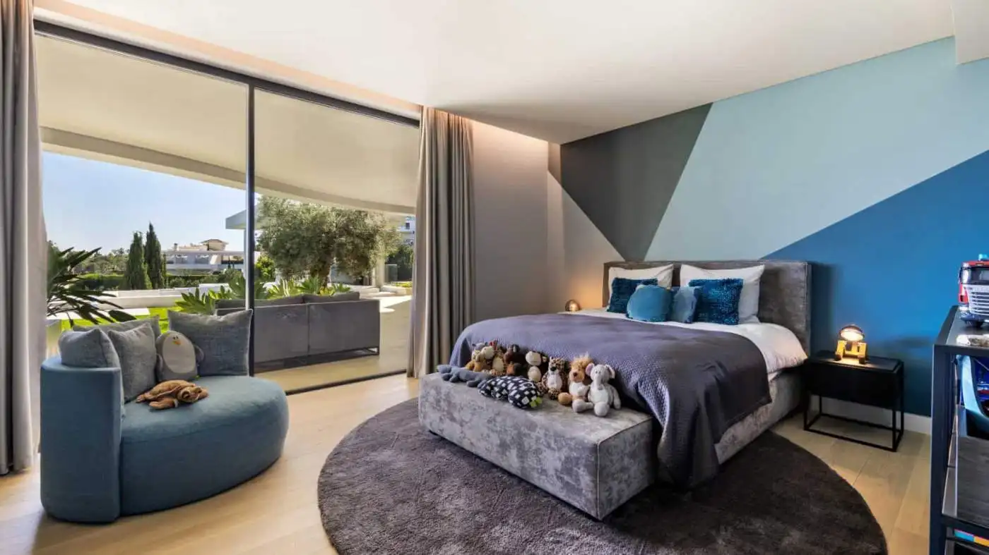 Elegant modern villa bedroom with stylish decor and large glass doors opening to a balcony.