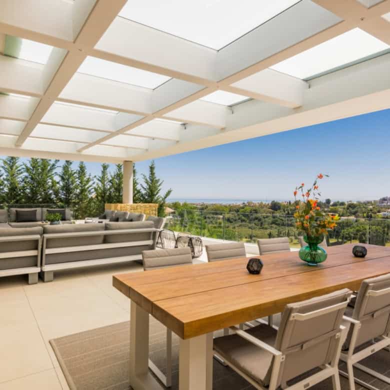 Spacious outdoor terrace of a modern villa overlooking lush greenery and distant landscape. Perfect.
