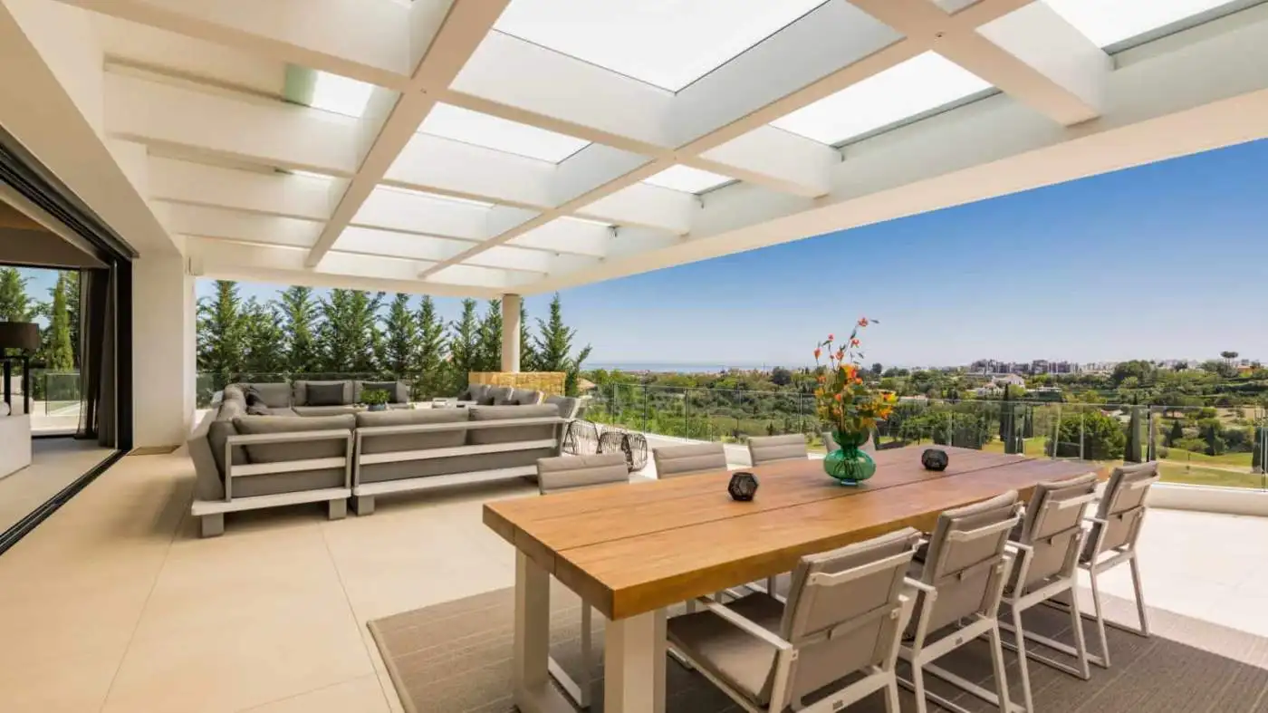 Spacious outdoor terrace of a modern villa overlooking lush greenery and distant landscape. Perfect.