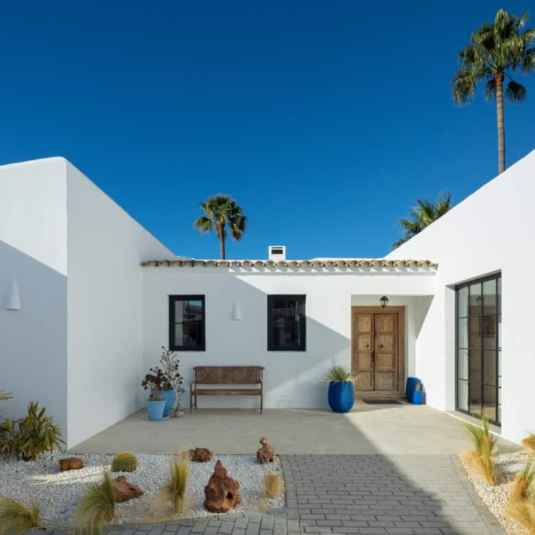 Beautiful exterior of Casa Teresita featuring white walls, blue pots, and desert landscaping under a.
