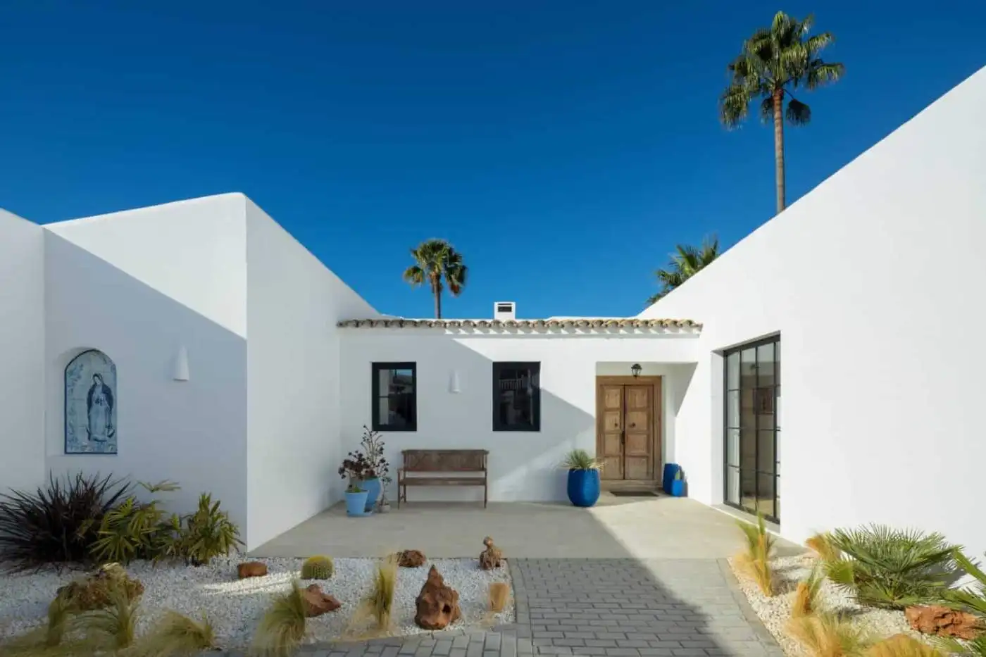 Beautiful exterior of Casa Teresita featuring white walls, blue pots, and desert landscaping under a.
