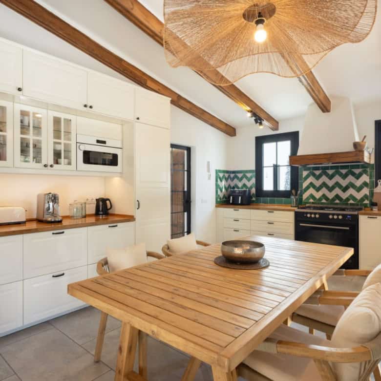 Modern kitchen with white cabinetry, wooden countertops, and stylish backsplash tiles.