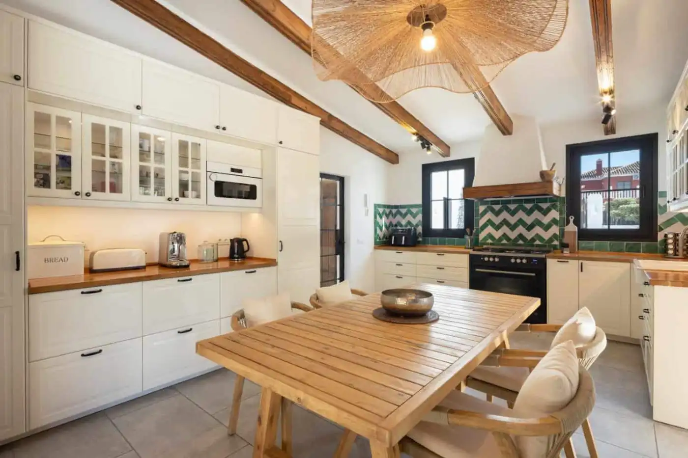 Modern kitchen with white cabinetry, wooden countertops, and stylish backsplash tiles.
