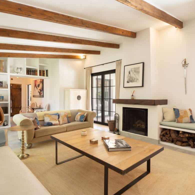 Bright and spacious living area in Casa Teresita with rustic wooden beams and cozy fireplace.