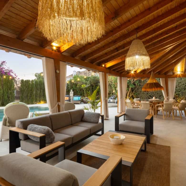 Spacious covered patio with seating, pool, and garden at Casa Teresita property.
