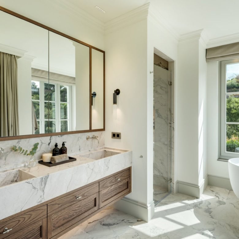 Elegant modern bathroom with marble finishes and large windows overlooking lush greenery.