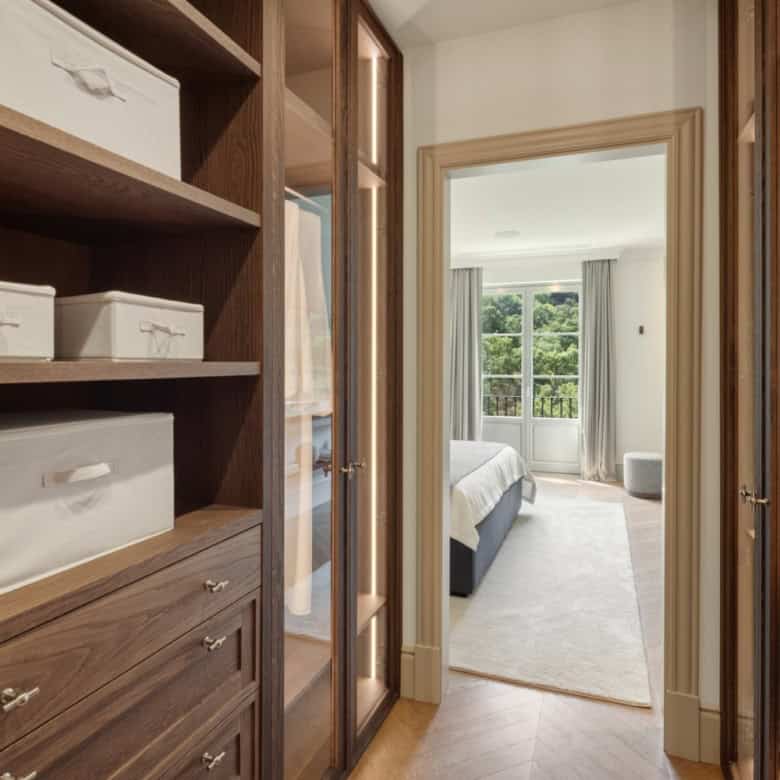 Elegant walk-in closet with wooden shelves and storage boxes.