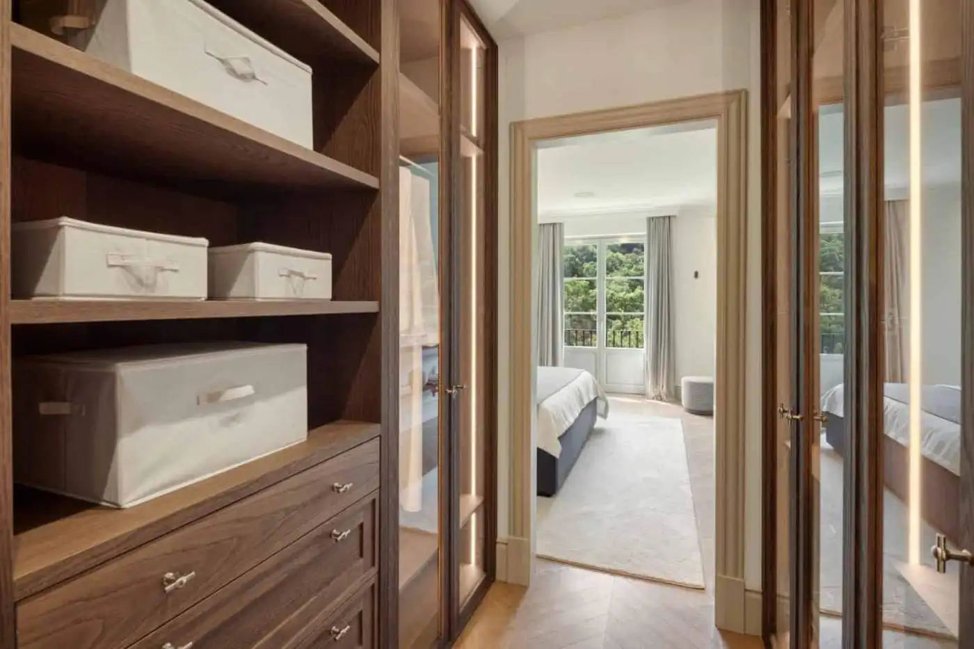 Elegant walk-in closet with wooden shelves and storage boxes.