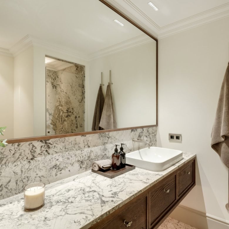 Luxurious bathroom with marble countertop, stylish towels, and contemporary design elements.