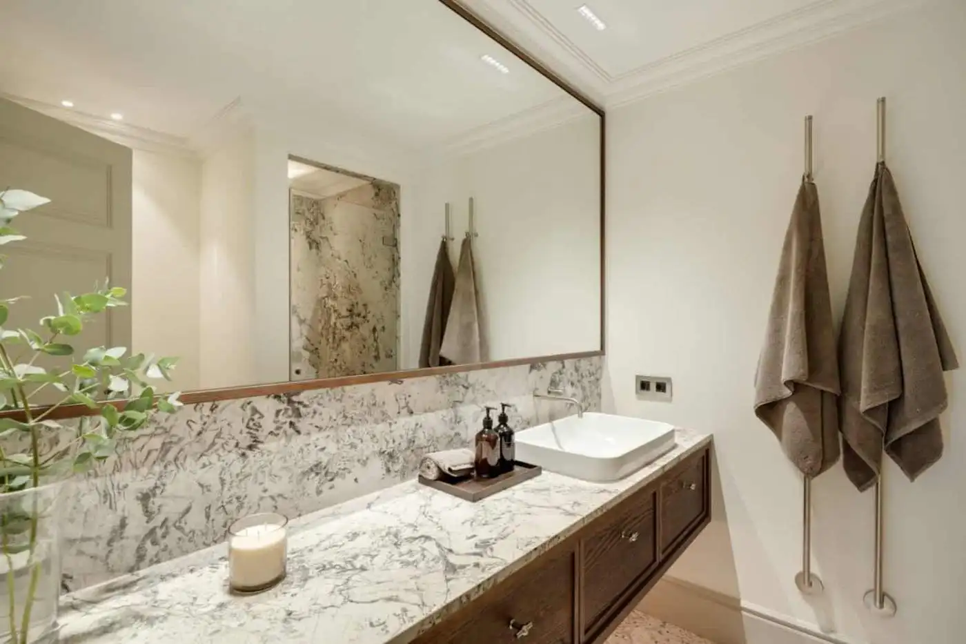 Luxurious bathroom with marble countertop, stylish towels, and contemporary design elements.