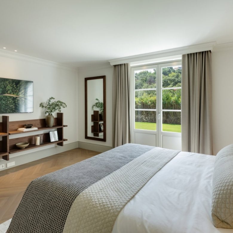 Modern bedroom with large window overlooking lush greenery in La Zagaleta. Elegant decor and spaciou.