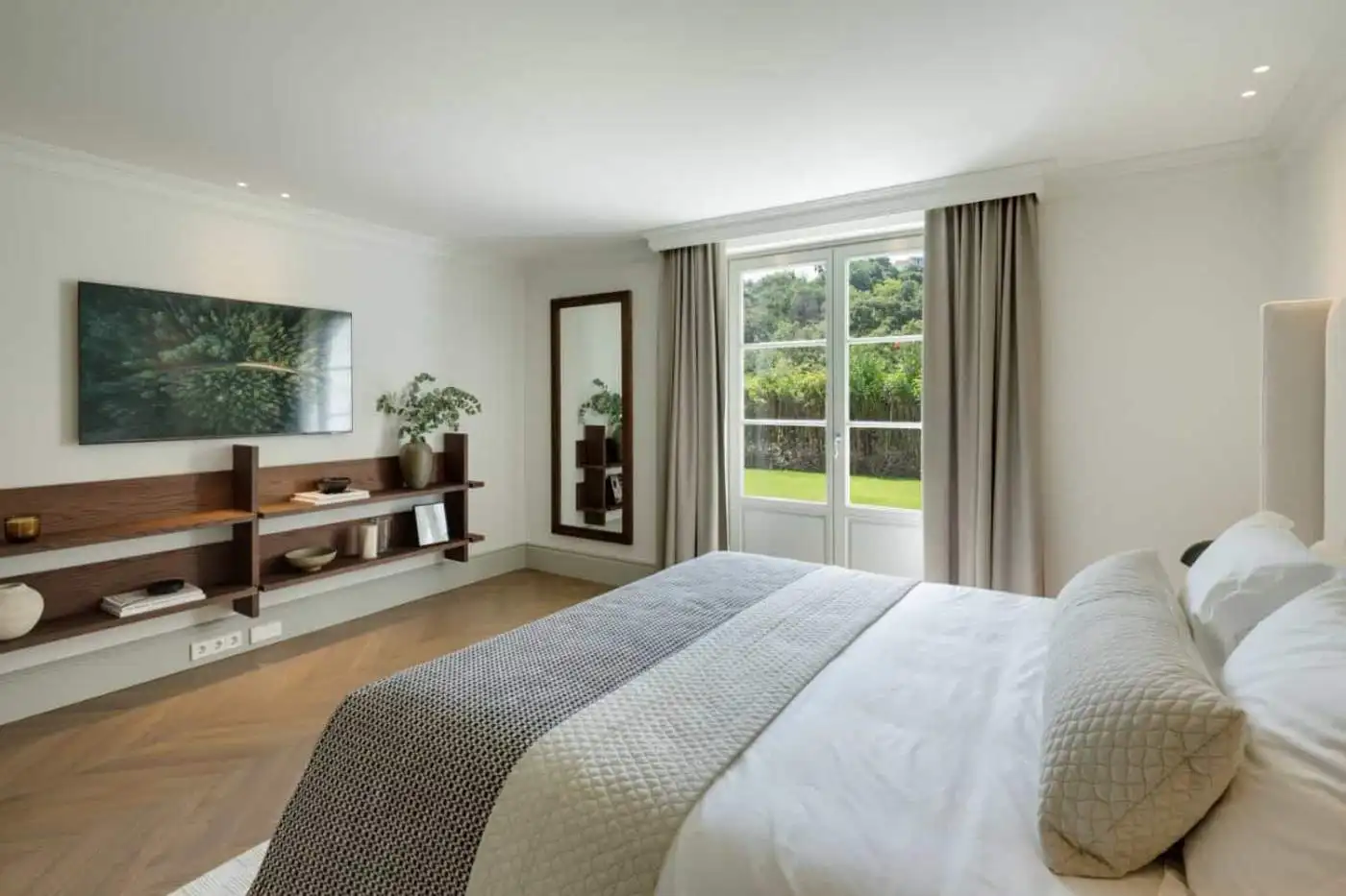 Modern bedroom with large window overlooking lush greenery in La Zagaleta. Elegant decor and spaciou.