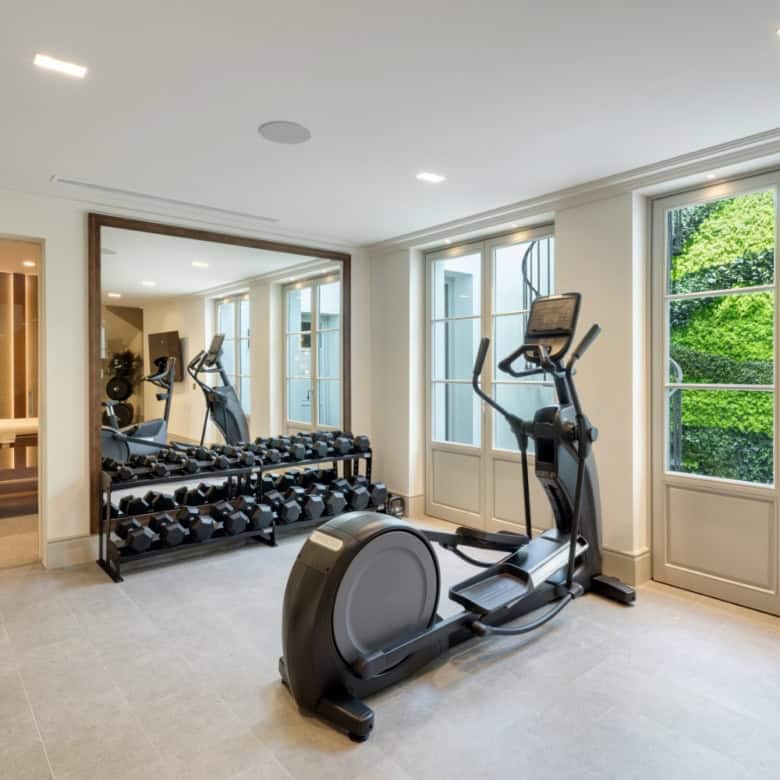 Modern home gym with cardio equipment and free weights in a bright, spacious room.