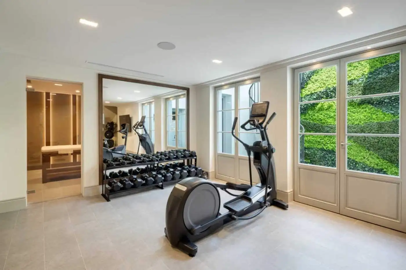 Modern home gym with cardio equipment and free weights in a bright, spacious room.