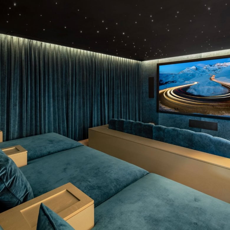 Luxurious home theater with plush blue seating and a large screen showcasing scenic mountain views.
