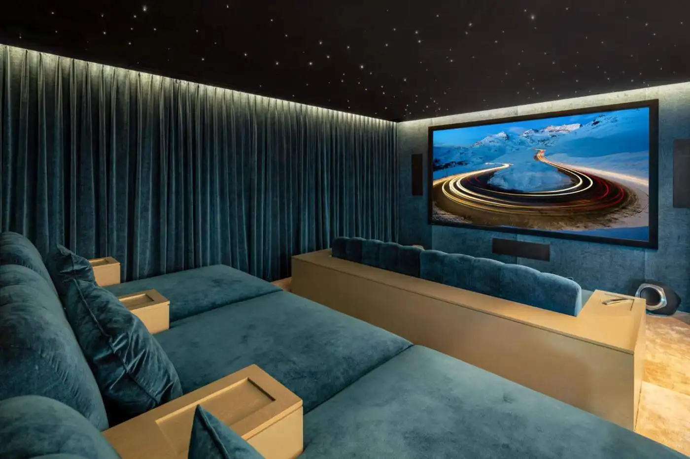 Luxurious home theater with plush blue seating and a large screen showcasing scenic mountain views.