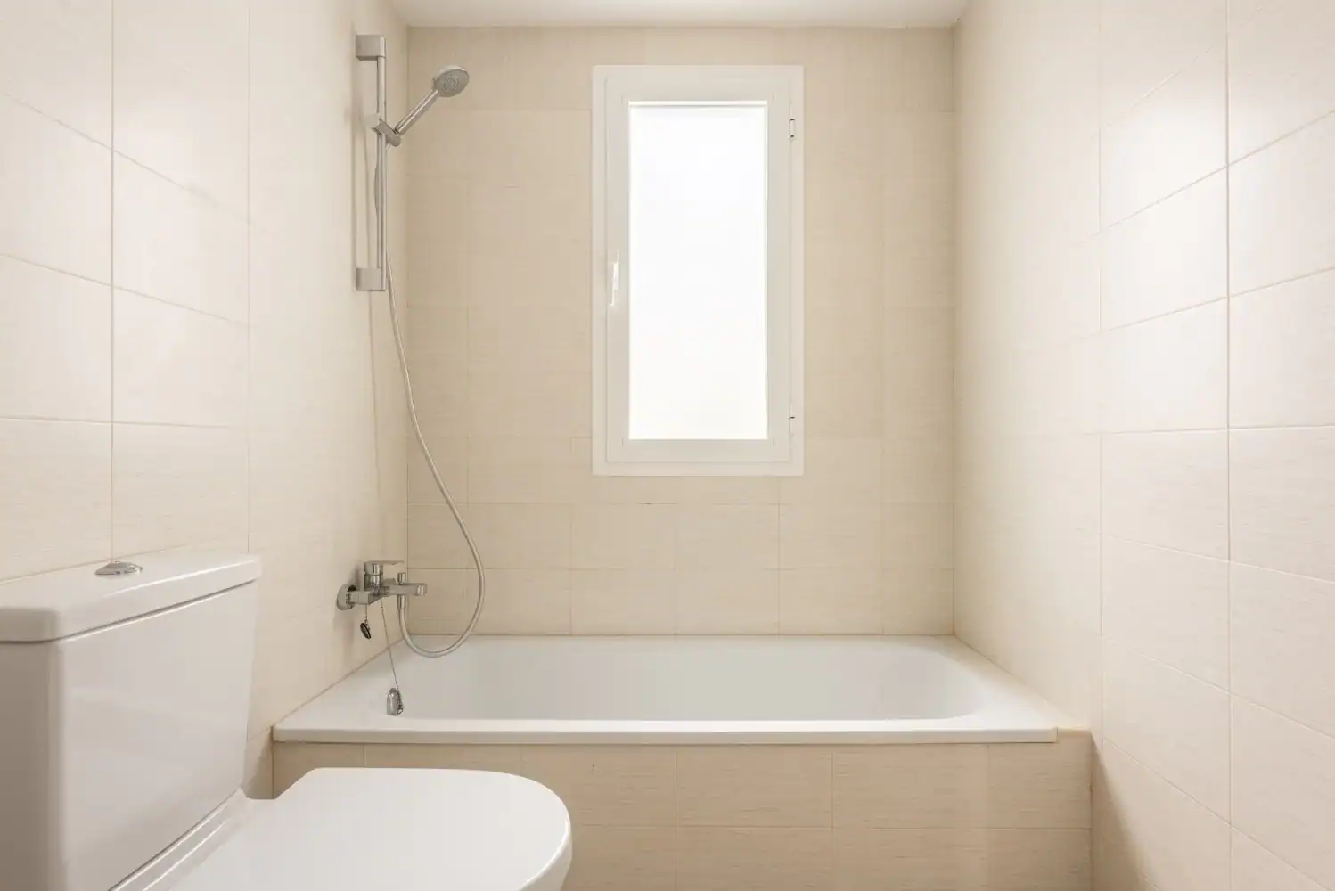 Bathroom with bathtub and shower in Puerto Banus townhouse, featuring neutral tiles and a frosted wi.