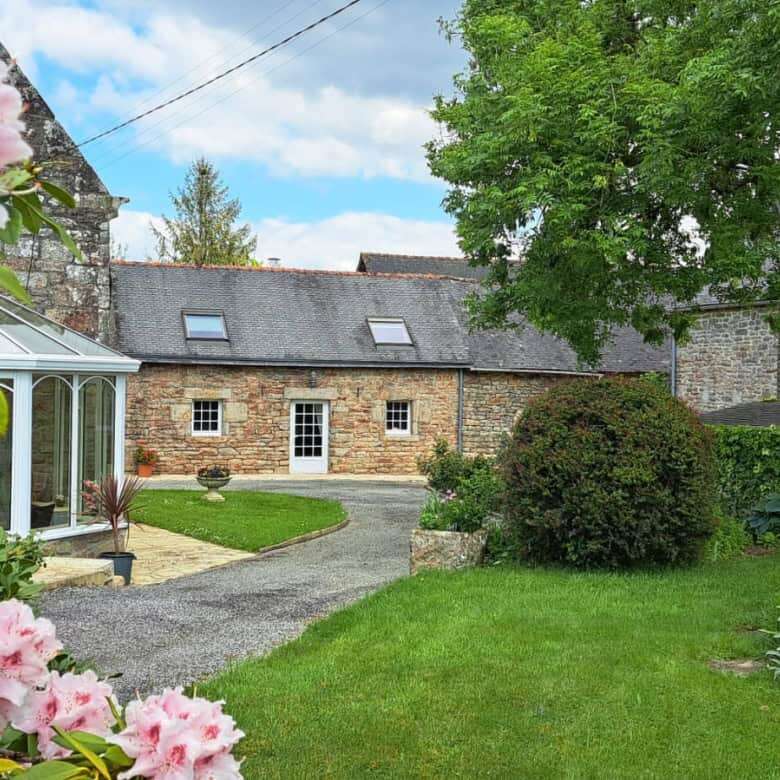 Elegant 12-bedroom estate for sale in Scaer, Brittany, featuring beautiful gardens and historic arch.