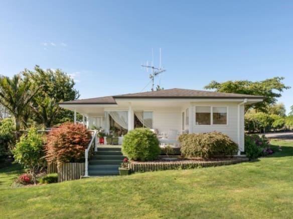 Cozy white cottage with lush garden and vibrant greenery in Tauranga, Bay of Plenty, New Zealand.