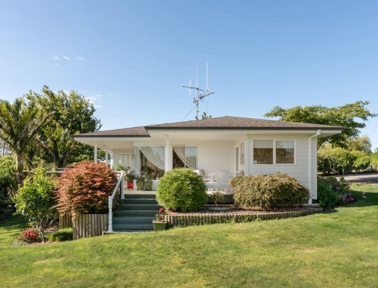 Cozy white cottage with lush garden and vibrant greenery in Tauranga, Bay of Plenty, New Zealand.