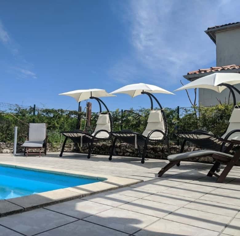 Outdoor pool area with sun loungers and umbrellas at a luxury French estate.