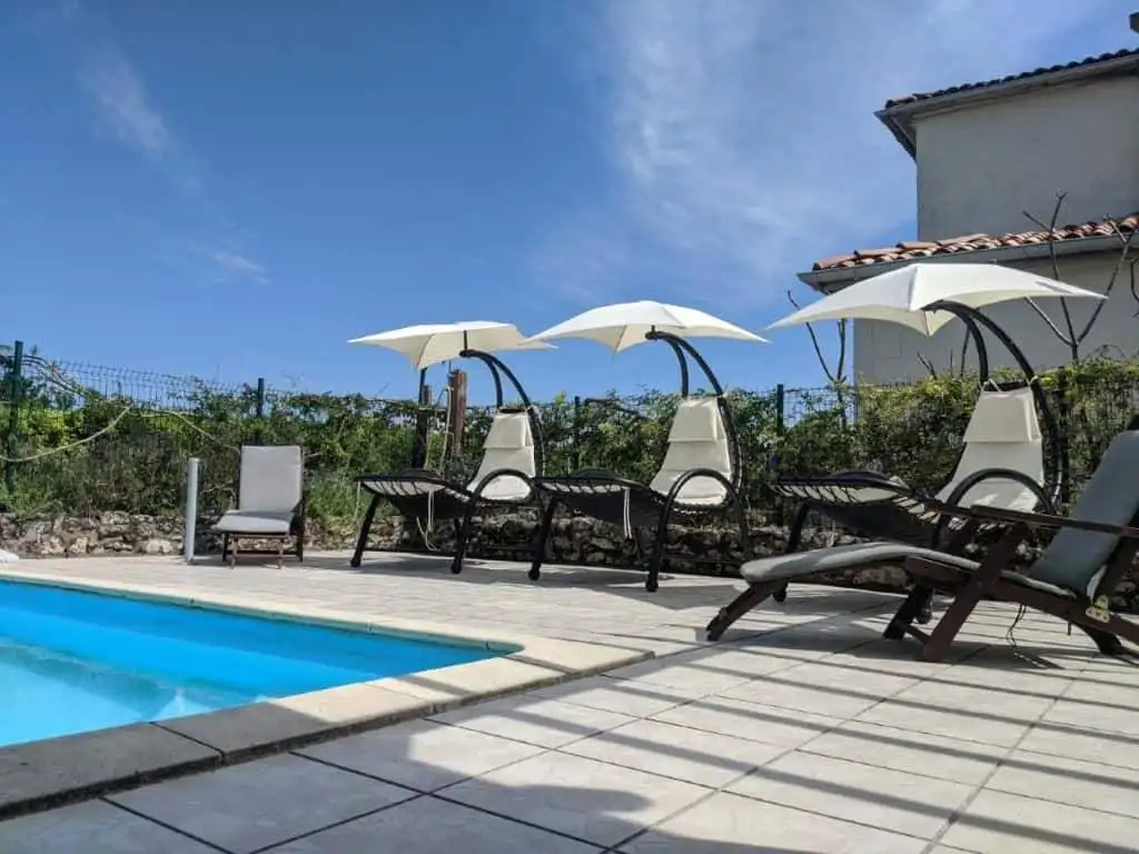 Outdoor pool area with sun loungers and umbrellas at a luxury French estate.