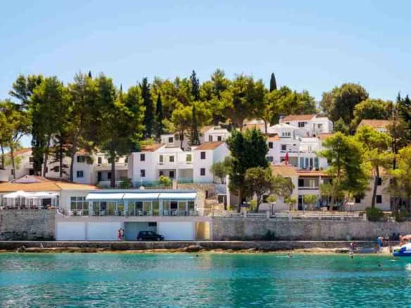 Beautiful seaside view of Lumbarda resort with white villas and lush greenery in Korčula, Croatia.