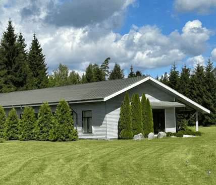 Modern farm building with lush greenery in Kekava, Latvia.