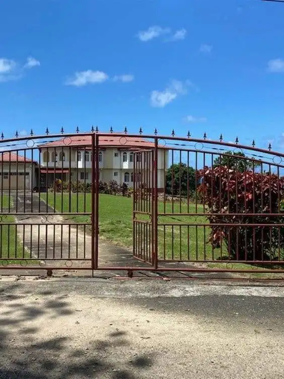 Gated entrance to a luxurious 8-bedroom estate in Port Antonio, Jamaica, featuring lush gardens and.