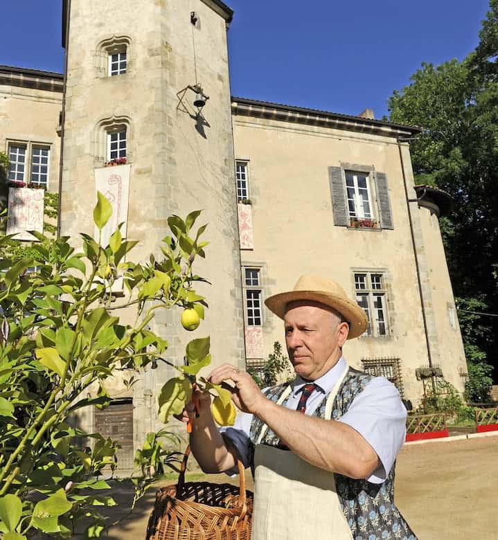 Château de la Chassaigne with a man harvesting fruit in the garden, historic French estate for sale.