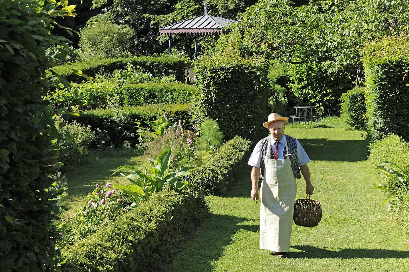 Stunning French Garden with Man in Traditional Attire Beautiful landscaped garden in Thiers, France, featuring lush greenery and a charming gazebo.