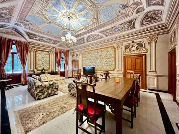 Elegant historic living room with ornate ceiling and classic furnishings.