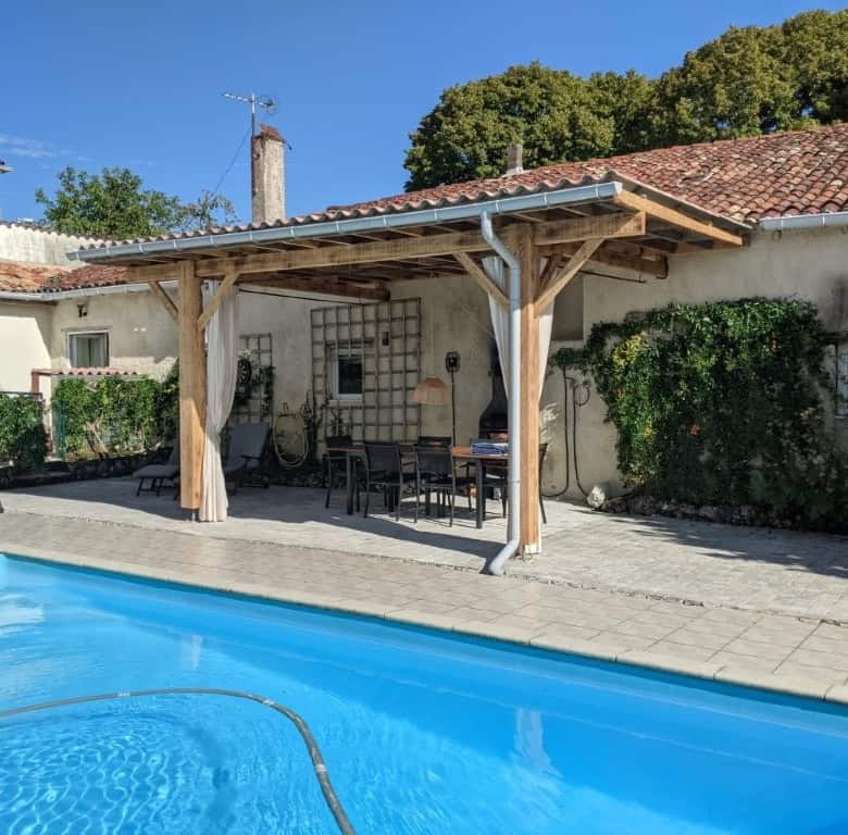 Beautiful outdoor pool area with shaded dining space in a French countryside estate.