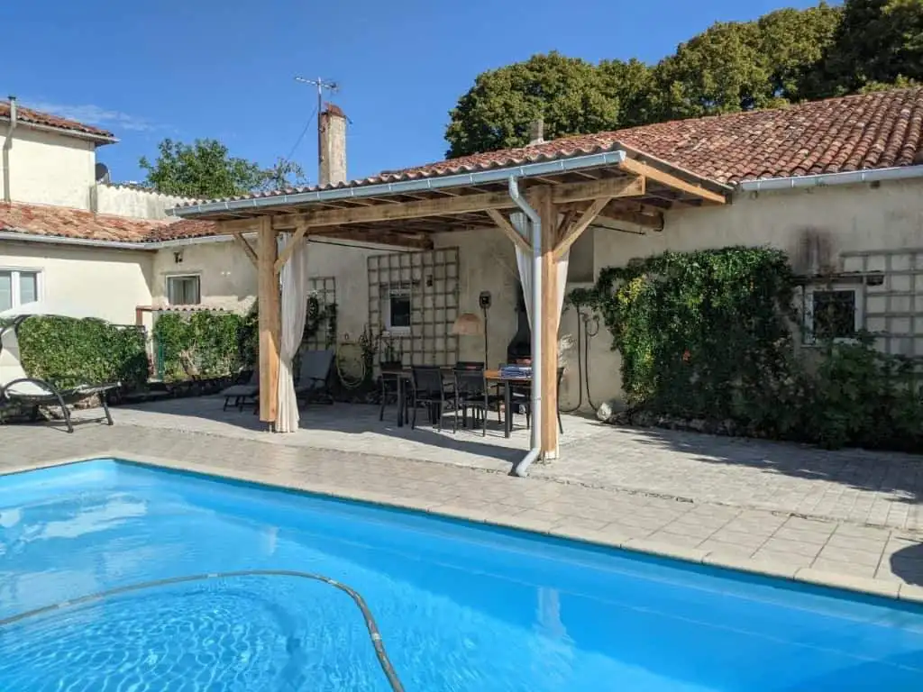 Beautiful outdoor pool area with shaded dining space in a French countryside estate.
