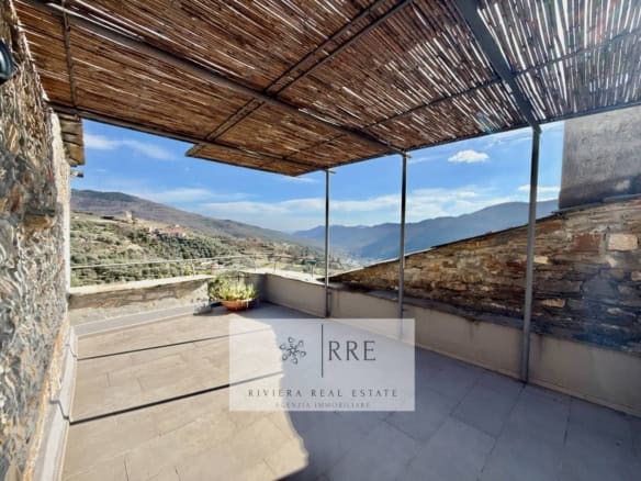 Panoramic terrace overlooking mountains with shaded bamboo roof.