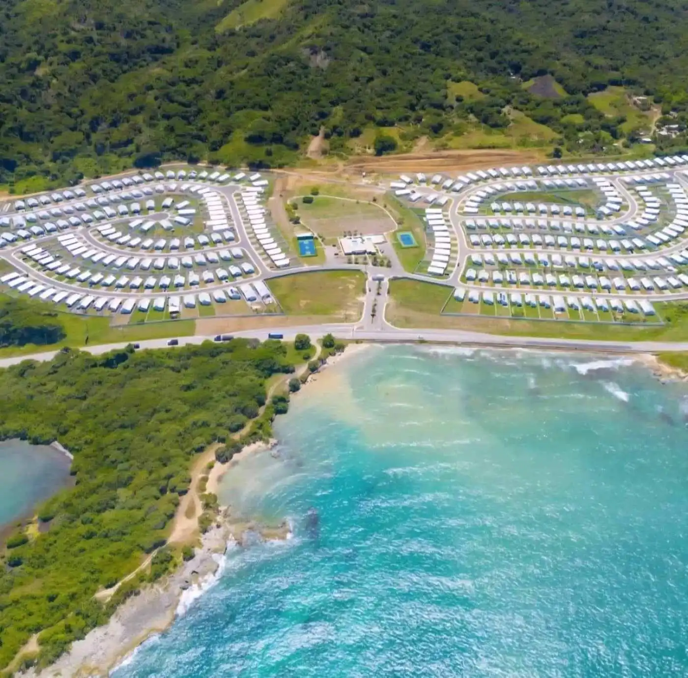 Luxury 3 Bed House For Sale In Sunshine Seashore Ocean Pointe Lucea Jamacia Aerial view of Ocean Pointe resort with luxury homes and lush greenery near the Caribbean coast.