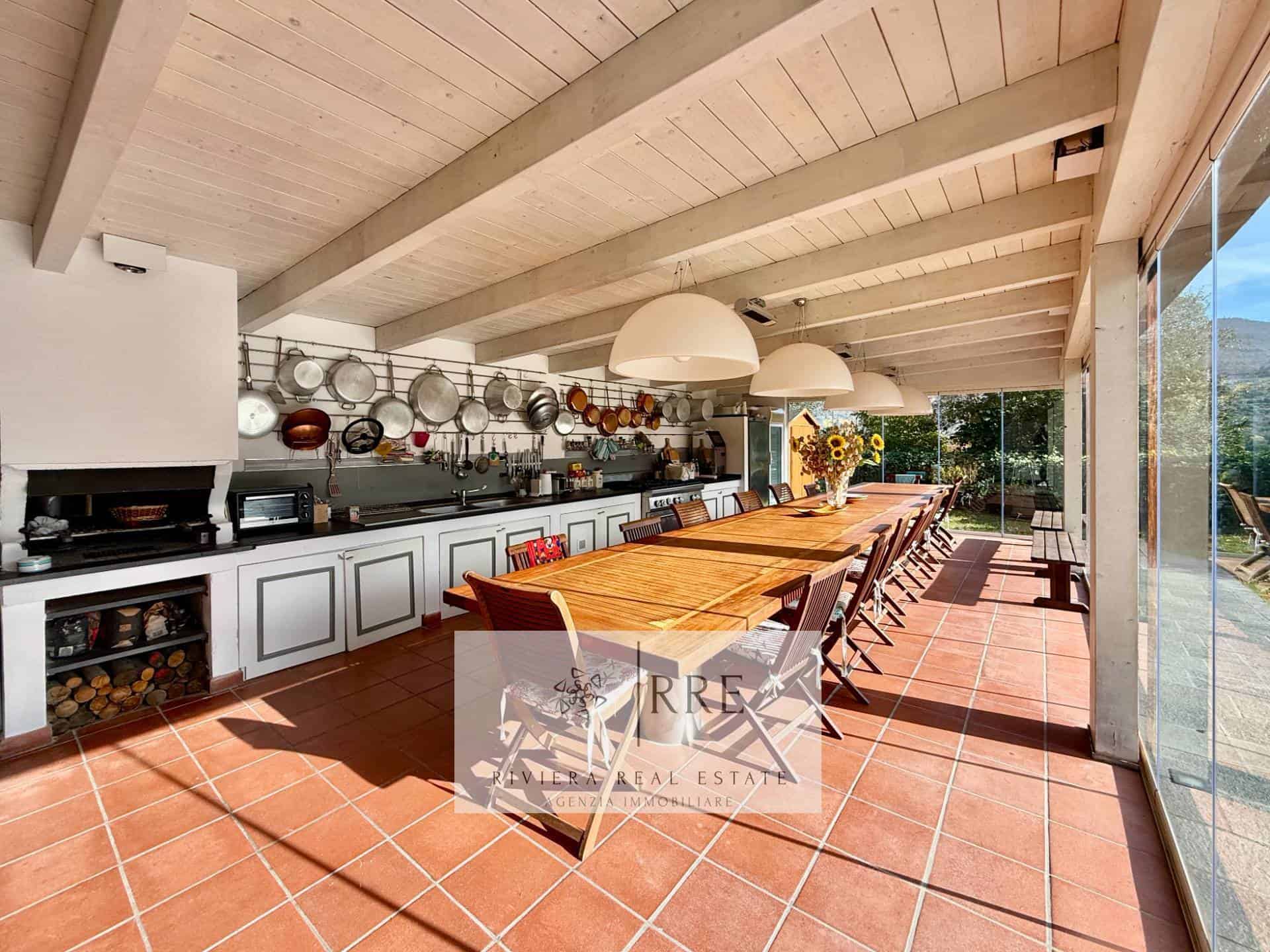 Bright indoor kitchen with large windows and wooden ceiling beams.