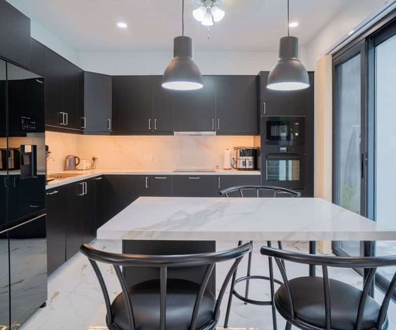 Elegant black kitchen with marble island and modern appliances. Bright, spacious, and perfect for co.