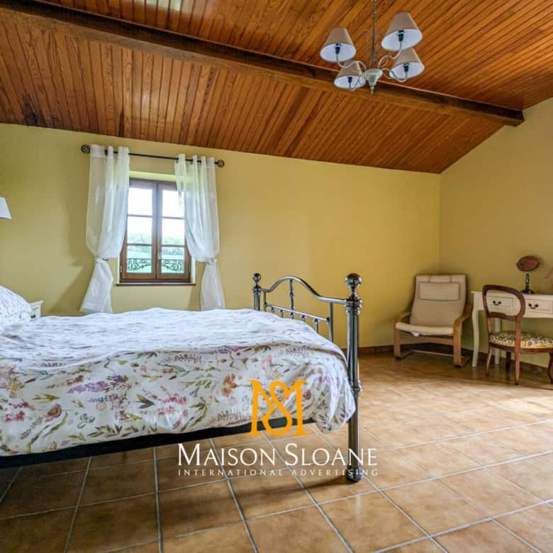 Elegant bedroom with vintage decor and wooden ceiling in a French countryside estate.