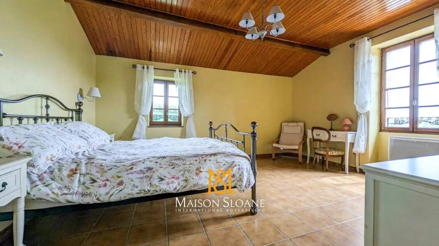 Elegant bedroom with vintage decor and wooden ceiling in a French countryside estate.