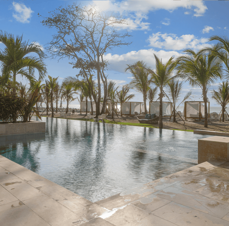 Beachfront pool with palm trees and cabanas at Surfside - Playa Caracol, Panama.