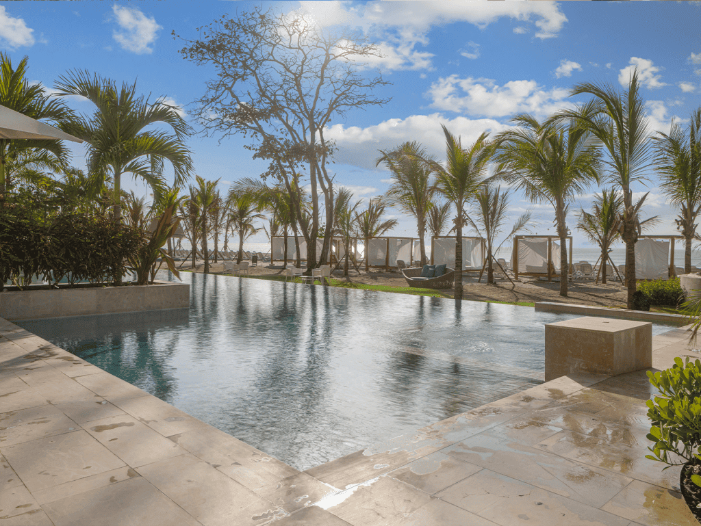 Beachfront pool with palm trees and cabanas at Surfside - Playa Caracol, Panama.