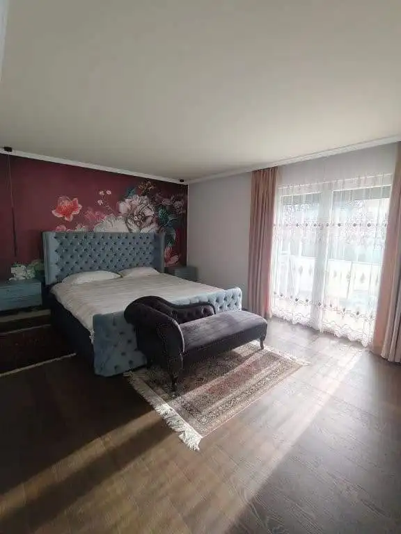 Elegant bedroom featuring a floral accent wall, a plush bed with tufted headboard, and a cozy bench.