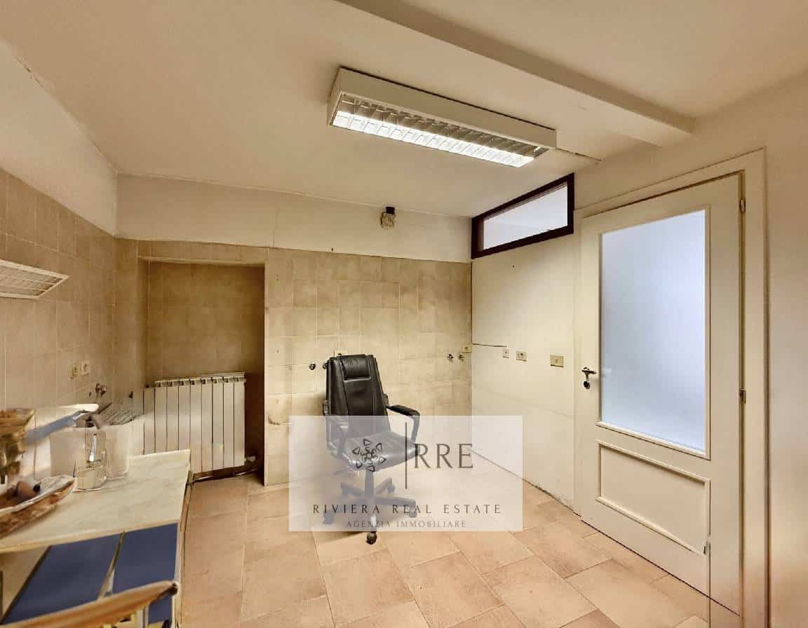 Office space with a door and frosted window, featuring beige tiled walls and a black office chair.
