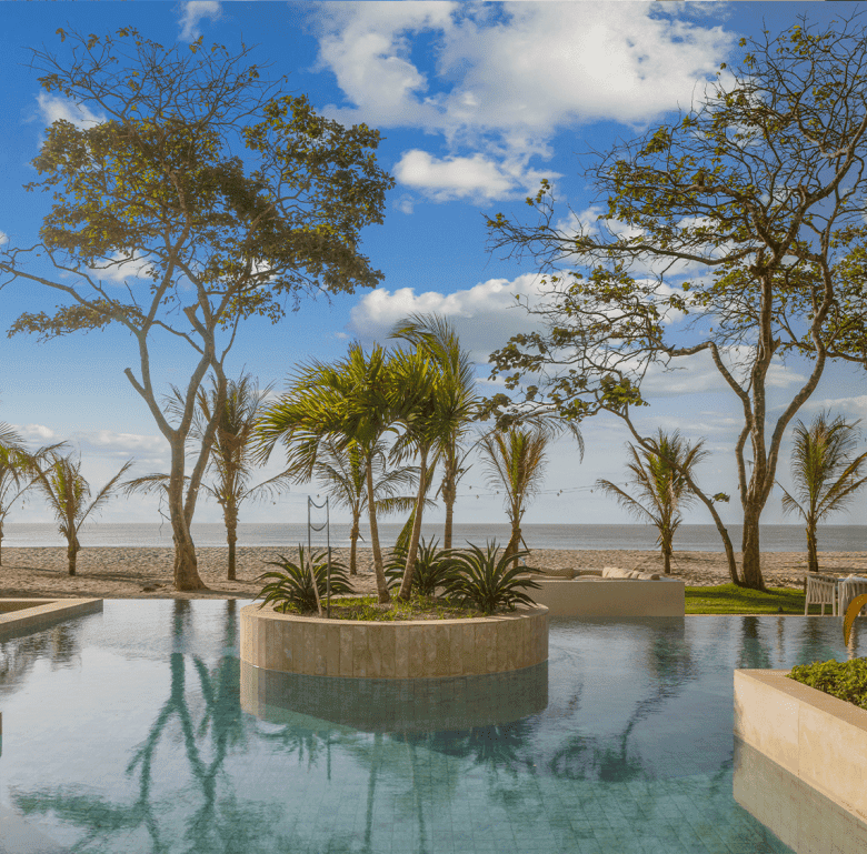 Beachfront pool at Surfside Playa Caracol, Panama, with palm trees and ocean views. Perfect for rela.